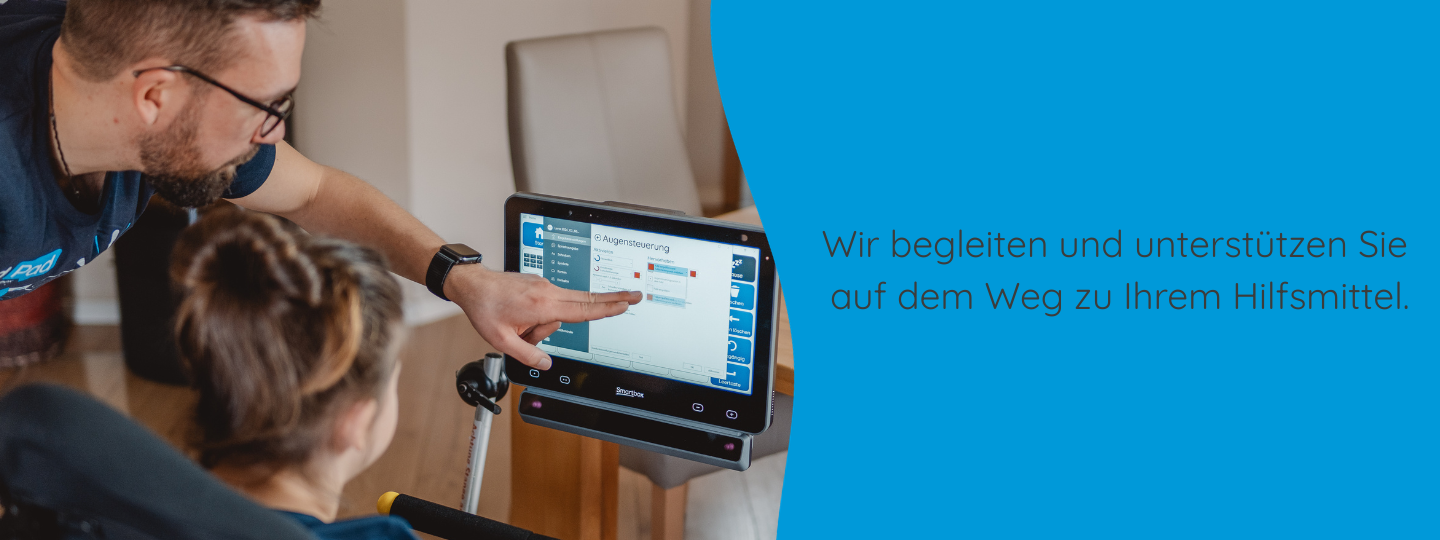 Ein Berater von REHAVISTA zeigt einer Frau im Rollstuhl etwas auf ihrem Sprachcomputer.
